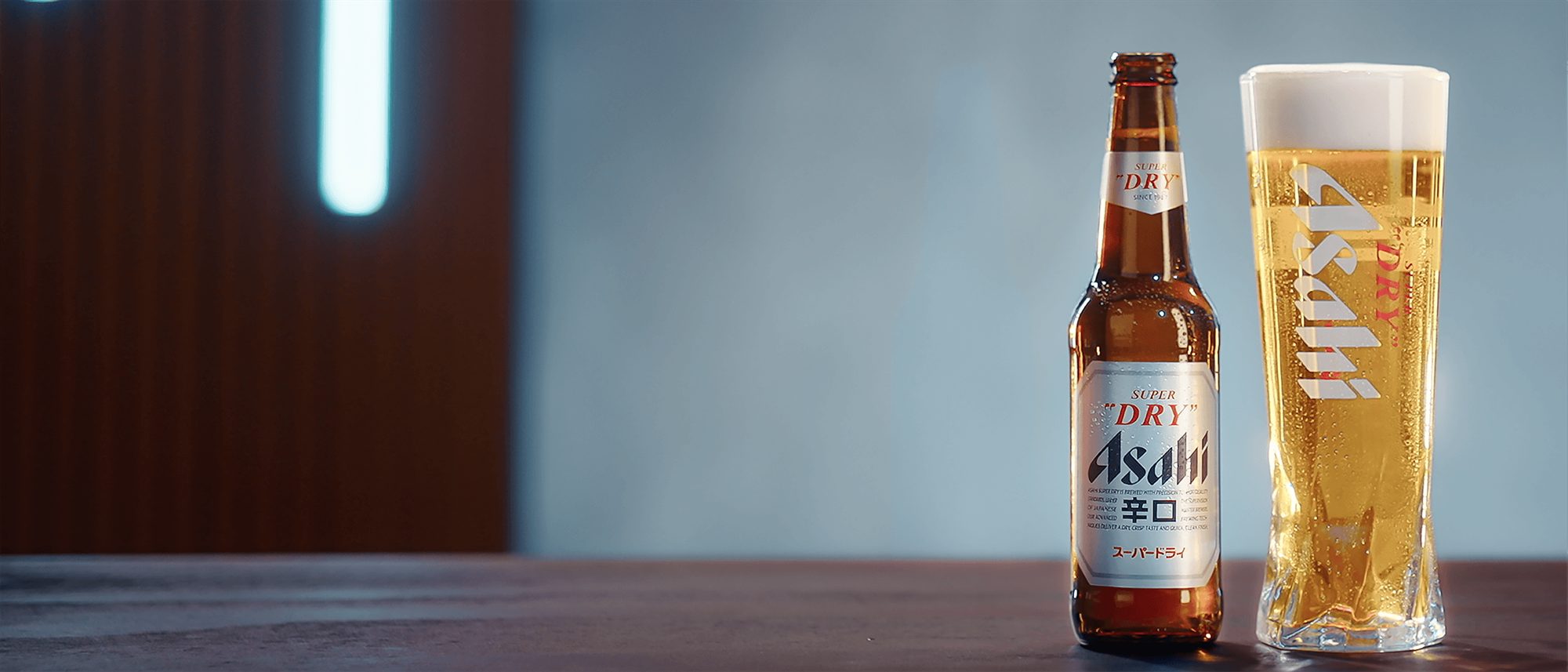 Asahi Super Dry bottle beside a freshly poured glass on a bar counter